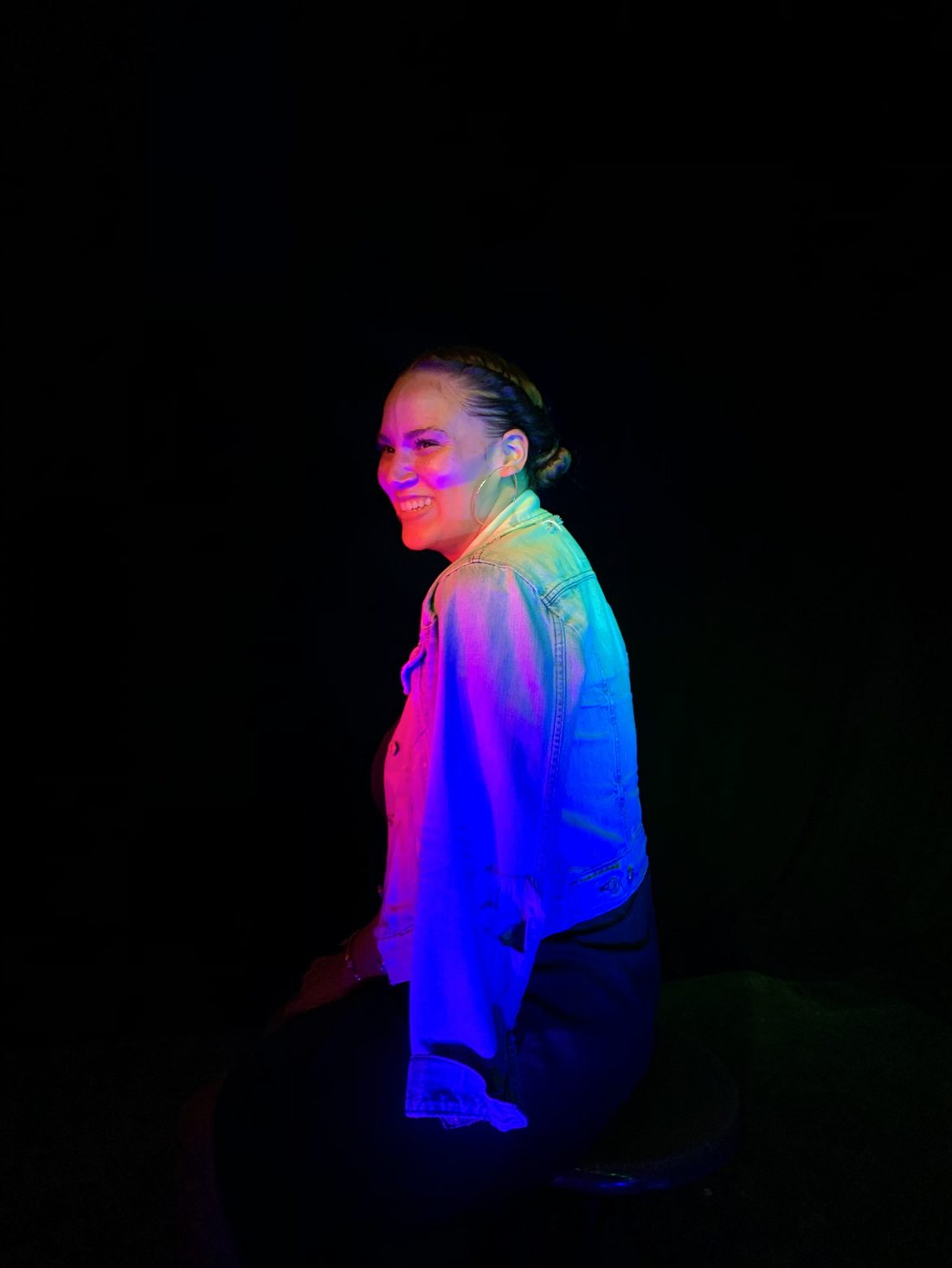 LaMia Florence, smiling, lit in magenta and blue against a dark background